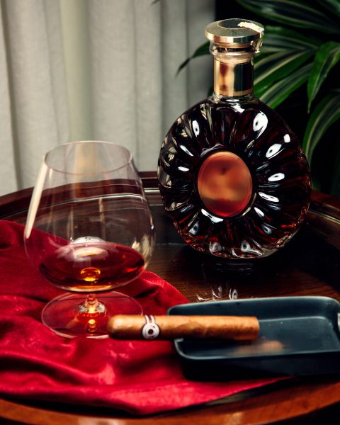 a glass and bottle of cognac and sigar